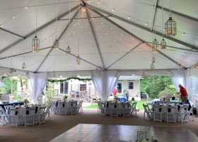 White Top Structure Tent with laydown floor and astroturf, swagged bistro lighting with candle lanterns and taffeta leg drapes