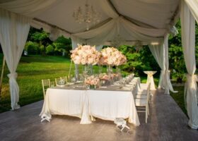 WHITE FRAME TENT WITH WOOD GRAIN VINYL FLOORING, CUSTOM TAFFETA SWAGGING, CHANDELIERS AND FANS